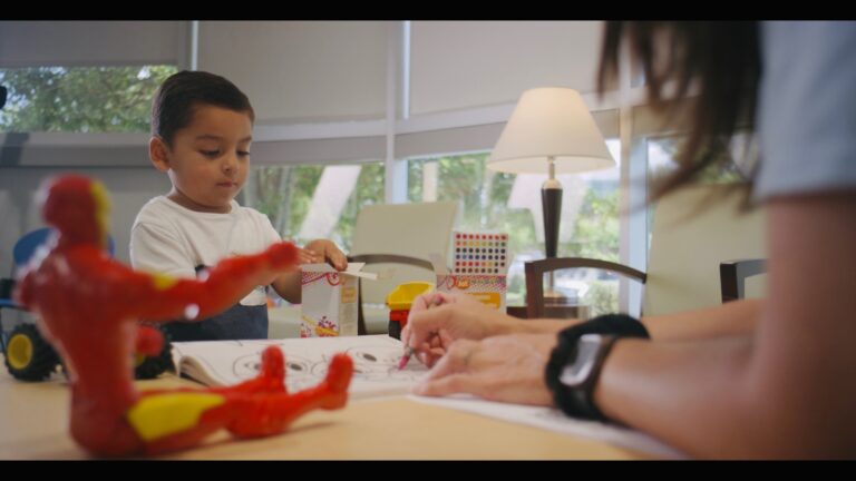 Child coloring with adult at a table.
